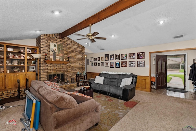 carpeted living room with a fireplace, a textured ceiling, ceiling fan, and wood walls