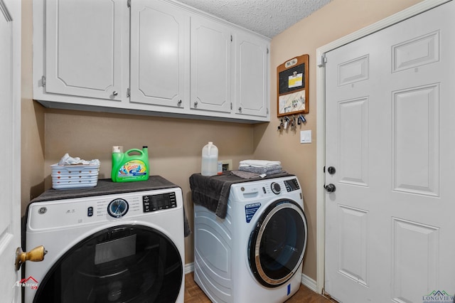 laundry area featuring washing machine and dryer, cabinets, and a textured ceiling