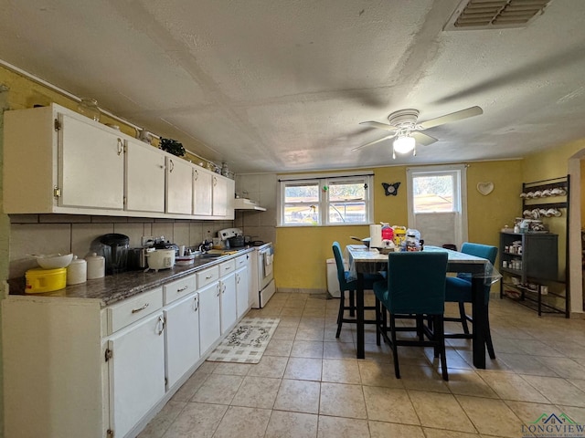 kitchen featuring white cabinets, light tile patterned floors, ceiling fan, white range with electric cooktop, and a textured ceiling