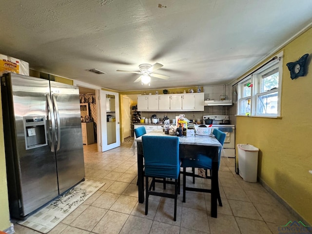 kitchen with white electric range, a kitchen bar, stainless steel fridge with ice dispenser, light tile patterned floors, and white cabinets