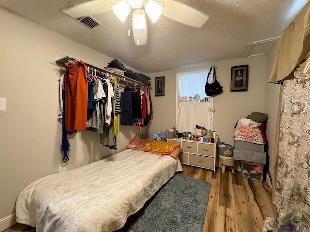 bedroom with dark hardwood / wood-style flooring, ceiling fan, and a textured ceiling