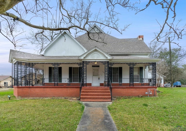 farmhouse with covered porch, a front lawn, and roof with shingles