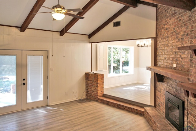 unfurnished living room with french doors, visible vents, a brick fireplace, wood finished floors, and beamed ceiling