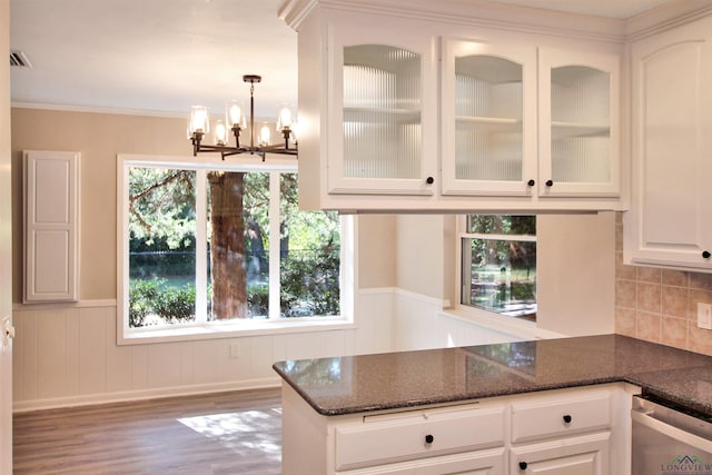 kitchen with glass insert cabinets, wainscoting, white cabinets, dark stone counters, and a peninsula