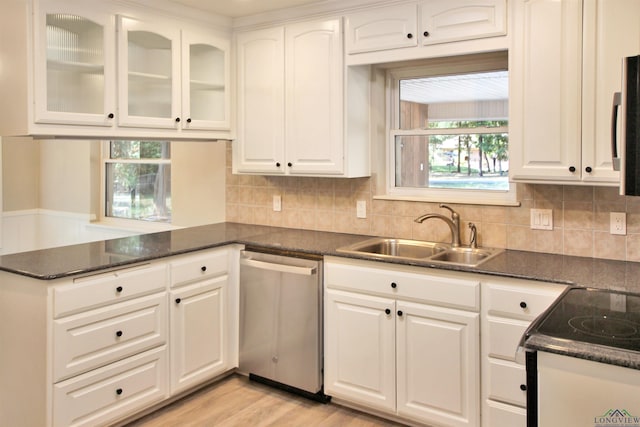 kitchen with white cabinets, a peninsula, light wood-type flooring, stainless steel dishwasher, and a sink