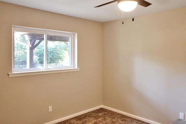 spare room with baseboards, dark carpet, and a ceiling fan