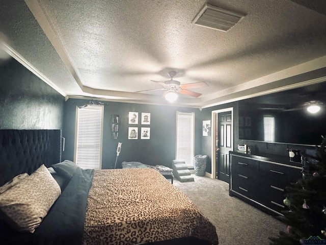 carpeted bedroom with a textured ceiling, a tray ceiling, and ceiling fan