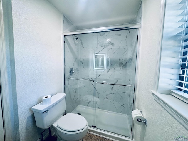 bathroom with toilet and a shower with shower door