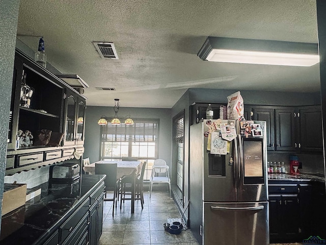 kitchen featuring stainless steel fridge, a textured ceiling, an inviting chandelier, and hanging light fixtures