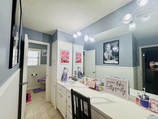 bathroom featuring vanity, a textured ceiling, wooden walls, tile patterned flooring, and toilet