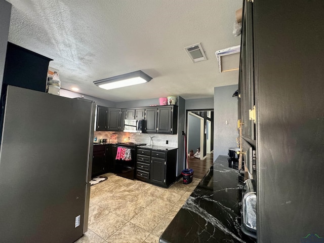 kitchen featuring tasteful backsplash, a textured ceiling, and appliances with stainless steel finishes