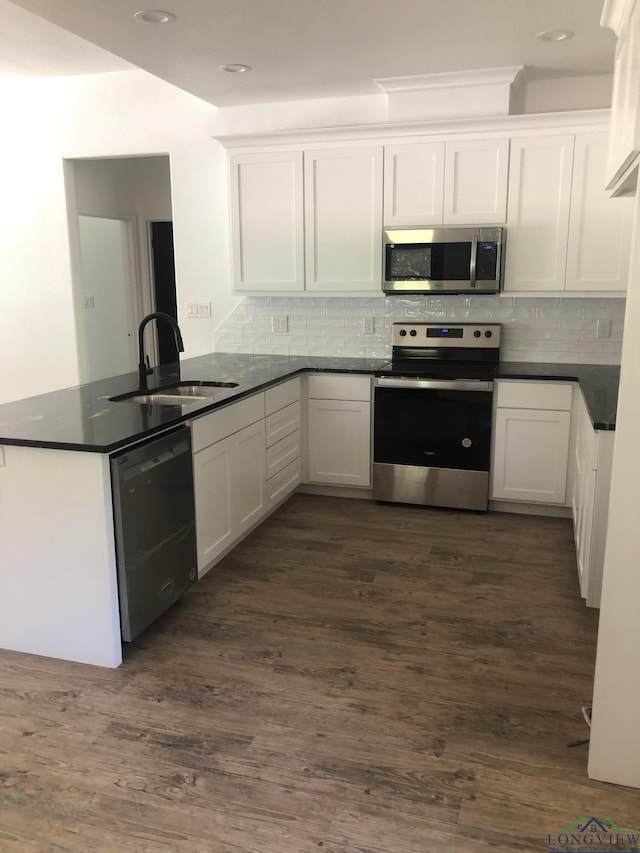 kitchen with white cabinets, kitchen peninsula, dark wood-type flooring, and appliances with stainless steel finishes