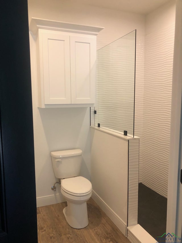 bathroom with hardwood / wood-style flooring, toilet, and a shower