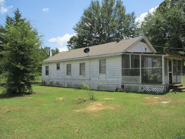 rear view of house with a sunroom and a yard