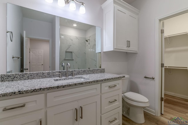 bathroom with hardwood / wood-style floors, vanity, toilet, and walk in shower