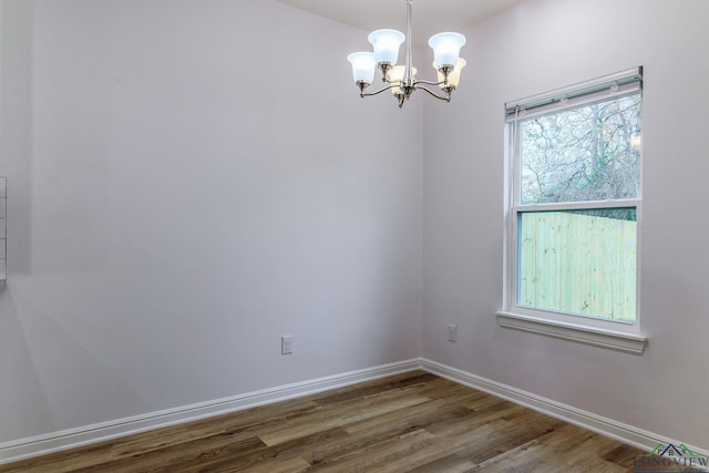 spare room featuring a chandelier and hardwood / wood-style floors