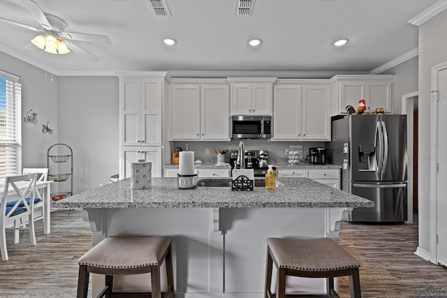 kitchen featuring a kitchen bar, white cabinets, stainless steel appliances, and ornamental molding