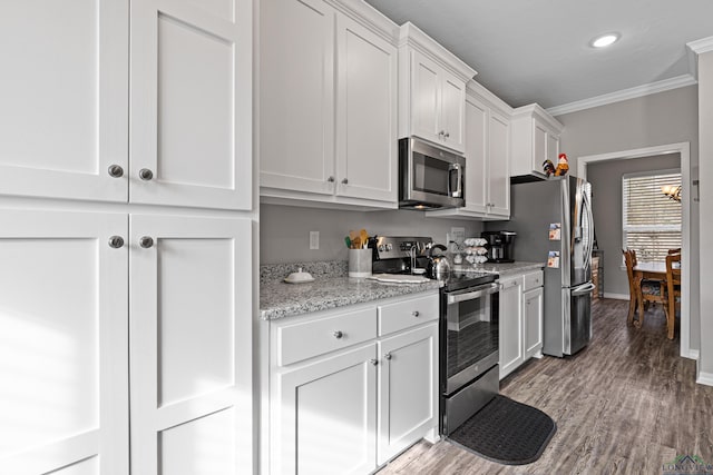 kitchen with white cabinets, crown molding, light stone countertops, appliances with stainless steel finishes, and light hardwood / wood-style floors