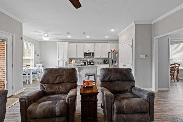 living room featuring hardwood / wood-style floors, ceiling fan, and crown molding