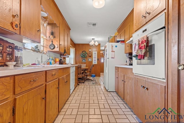 kitchen featuring wooden walls, sink, and white appliances