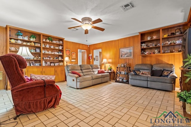 living room featuring ceiling fan and wooden walls