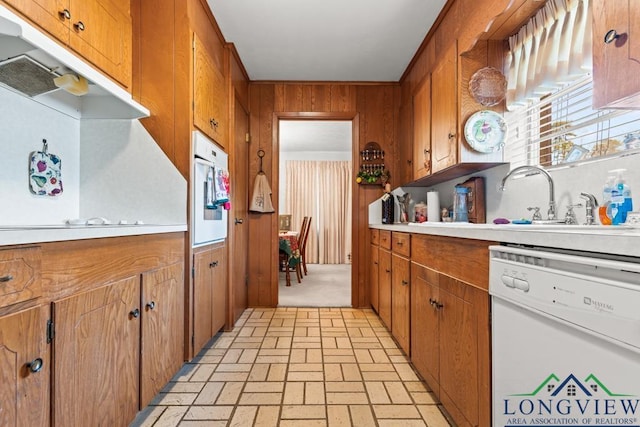 kitchen featuring dishwasher, sink, and wood walls