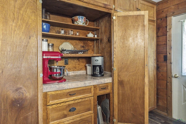 bar with tile countertops and wood walls