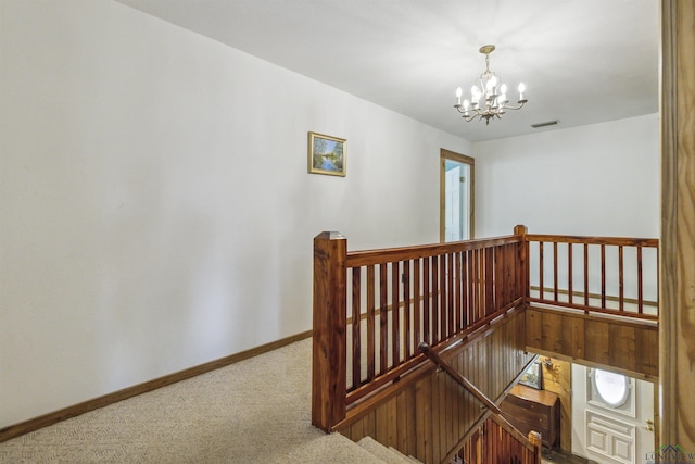 stairway with carpet and an inviting chandelier