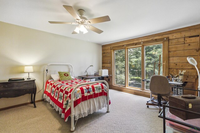 carpeted bedroom with ceiling fan and wood walls