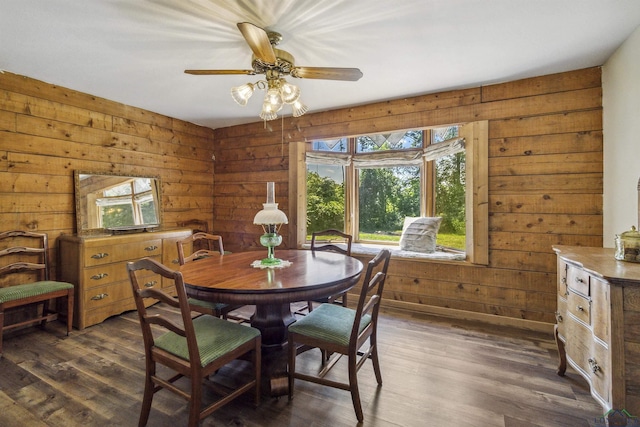 dining room featuring dark hardwood / wood-style floors, ceiling fan, and wooden walls