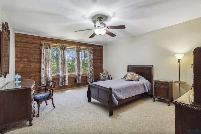 carpeted bedroom featuring ceiling fan and wood walls