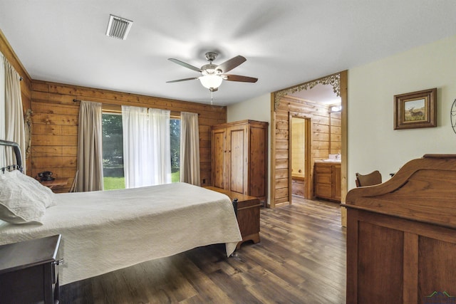 bedroom with wood walls, ceiling fan, dark hardwood / wood-style floors, and ensuite bath