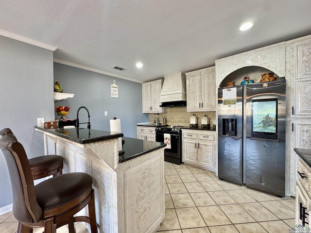 kitchen with black electric range, custom range hood, light tile patterned floors, a center island with sink, and a breakfast bar