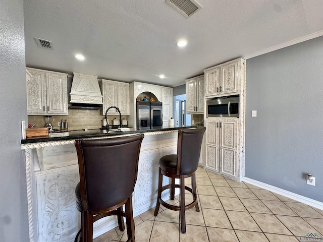 kitchen with custom exhaust hood, a breakfast bar area, stainless steel appliances, sink, and light tile patterned flooring