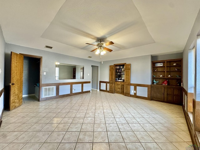 unfurnished living room featuring ceiling fan, a raised ceiling, and light tile patterned floors