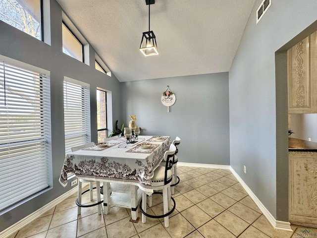 tiled dining area with a textured ceiling, vaulted ceiling, and plenty of natural light