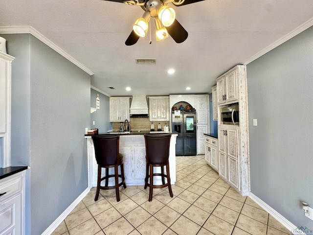 kitchen with stainless steel appliances, premium range hood, crown molding, and a breakfast bar area