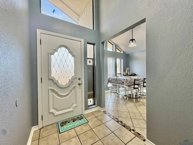 foyer entrance with light tile patterned flooring and vaulted ceiling