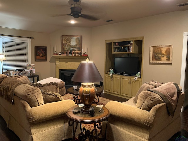 living area featuring ceiling fan, a fireplace, wood finished floors, and visible vents