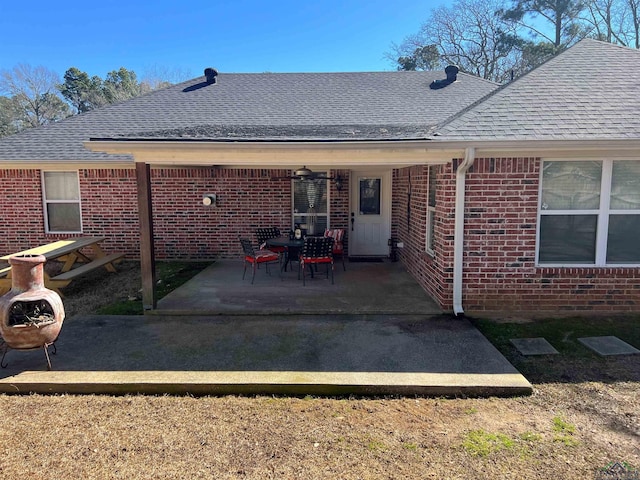 rear view of property with a patio area, a shingled roof, and brick siding