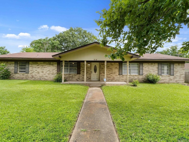 514 N St, Gilmer, TX 75644 - view of front of house with brick siding, a front lawn, and covered porch