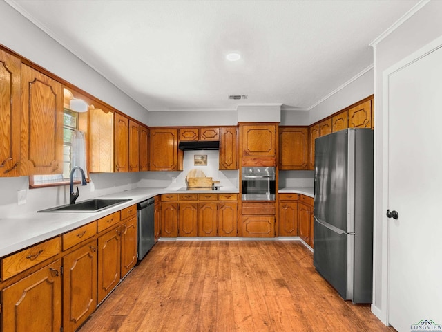 514 N St, Gilmer, TX 75644 - kitchen featuring appliances with stainless steel finishes, brown cabinetry, light countertops, under cabinet range hood, and ornamental molding