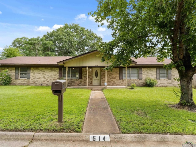 514 N St, Gilmer, TX 75644 - view of front facade with a front yard, brick siding, and covered porch