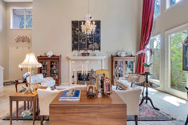 living room with a notable chandelier, a towering ceiling, a fireplace, and a wealth of natural light