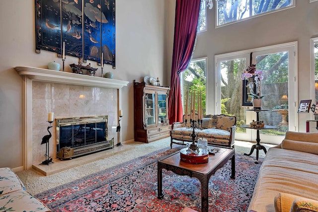 living room with a high ceiling and a tiled fireplace