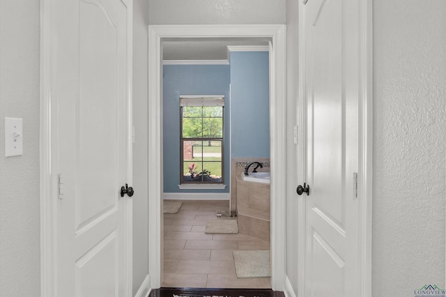hallway featuring a textured wall and crown molding