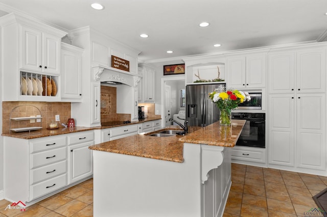 kitchen featuring dark stone countertops, white cabinetry, black appliances, a kitchen island with sink, and a sink