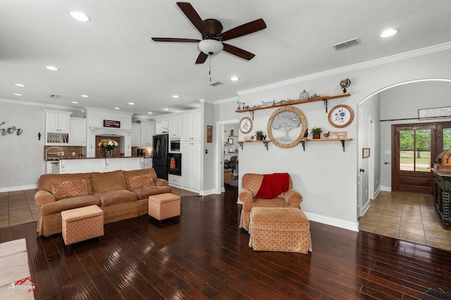 living room with arched walkways, ceiling fan, ornamental molding, and visible vents