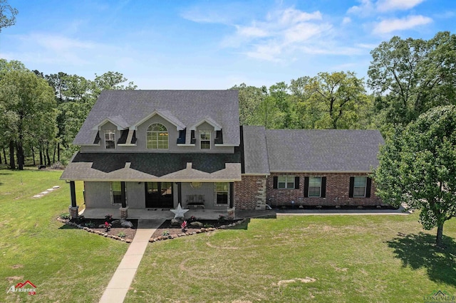 view of front of property with a shingled roof, a patio area, a front lawn, and brick siding