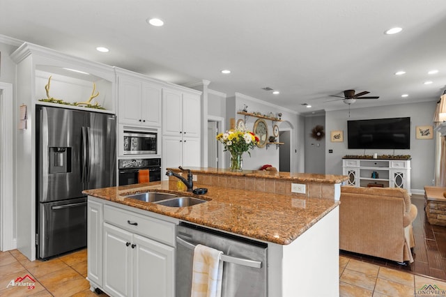 kitchen with appliances with stainless steel finishes, ornamental molding, light stone counters, ceiling fan, and a sink